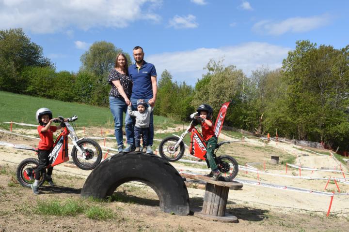 Familie Pichler auf einem großen Traktorreifen halb abgeschnitten die Jungs sind auf ihren e-Trial Bikes der Marke Oset.
